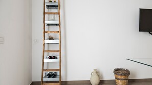 A room with a wooden ladder against a wall, a white vase, and a wicker basket on the floor.