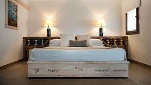 A bedroom with a wooden headboard, two bedside lamps, a bed with white linens, and a framed picture on the wall. - Room 'Riofavara Winery - Suite' with Private Terrace, Wi-Fi and Air Conditioning (Ispica)
