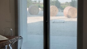 A view through a window of a room with a table and chair, and outside, hay bales are visible. - Room 'Riofavara Winery - Suite' with Private Terrace, Wi-Fi and Air Conditioning (Ispica)