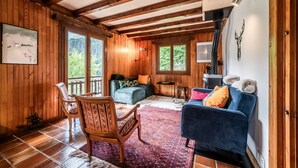 Ein Holzinterieur mit Kamin, einem blauen Sofa, einem gemusterten Teppich und einem Holzstuhl.
