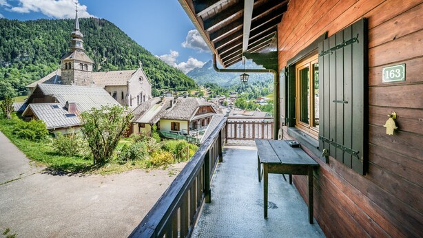 Ein Holzbalkon mit Blick auf eine Kirche und Berge.