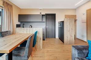 Una cocina moderna con armarios grises, una mesa de comedor de madera y un sofá con un cojín azul.