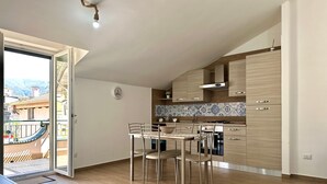 Una cucina moderna con mobili in legno, un tavolo da pranzo con sedie e vista attraverso una porta aperta.