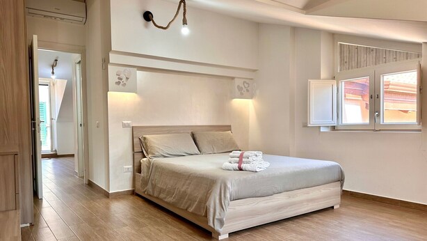 Una camera da letto con un letto, lampade sui comodini, una finestra e una porta.