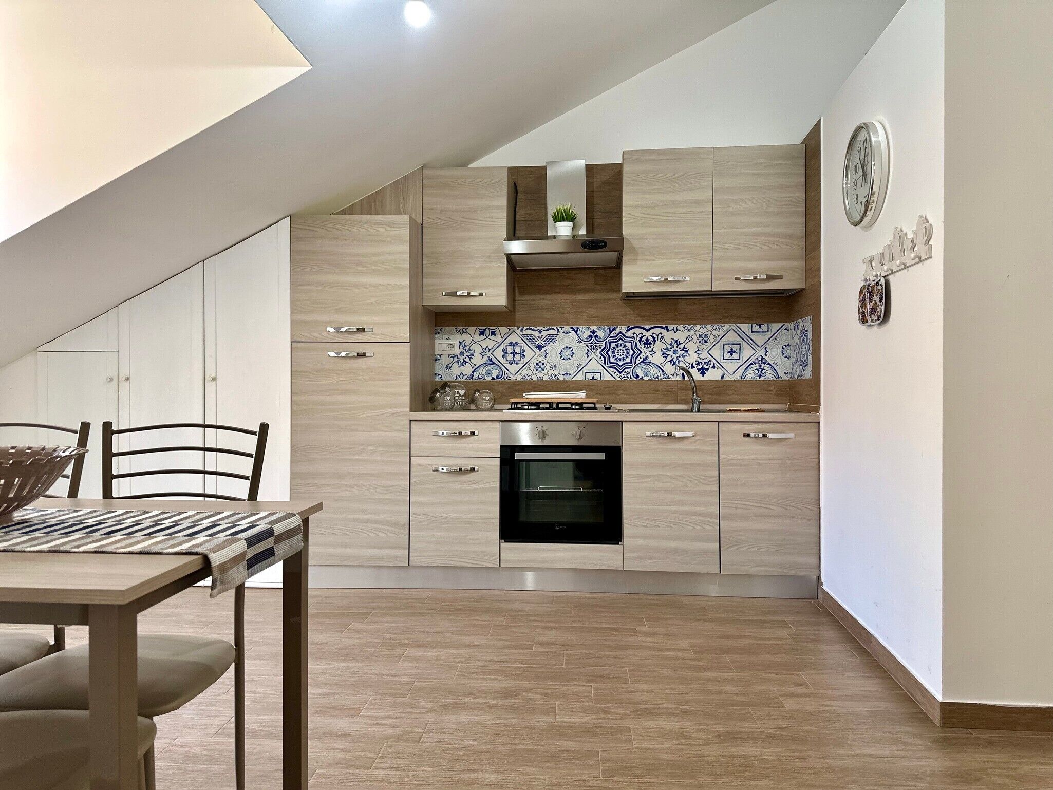 Una cocina moderna con armarios de madera, horno empotrado y salpicadero de azulejos.