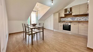 Una cucina moderna con mobili in legno, zoccolo in piastrelle e zona pranzo con tavolo e sedie.