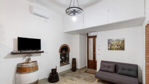Una sala de estar con televisor, sofá, chimenea y puerta.