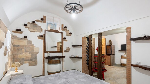 Un dormitorio con una cama, cabecera de madera, un espejo, pared de piedra y pared de ladrillo.