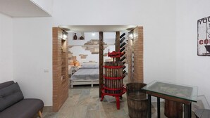 Una habitación moderna con una cama, una mesa de vidrio, un botiquín de barca roja y una pared de ladrillo.