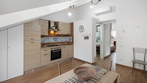 Cozinha moderna com armários de madeira, painel de azulejos e área de jantar com mesa e cadeiras de madeira.