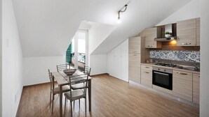 Cozinha moderna com área de jantar, piso de madeira e teto inclinado.