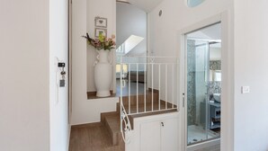 A staircase with a white railing, a white vase with flowers, and a bathroom with a glass shower door. - Apartment 'Tramonto' with Mountain View, Wi-Fi and Air Conditioning (Pimonte)