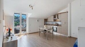 A modern kitchen with a dining area, a large window with a view, and a ceiling fan. - Apartment 'Tramonto' with Mountain View, Wi-Fi and Air Conditioning (Pimonte)