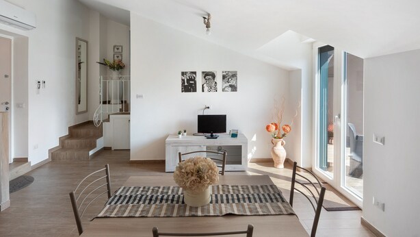 A modern living room with a dining area, a staircase, and a TV on a white cabinet. - Apartment 'Tramonto' with Mountain View, Wi-Fi and Air Conditioning (Pimonte)