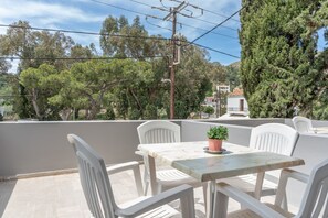 A terrace with a table and chairs, a potted plant, and a view of trees and buildings. - Apartment 'No 10' with Shared Pool, Wi-Fi and Air Conditioning (Kalymnos)