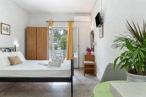 A bedroom with a bed, a wooden wardrobe, a small table with a plant, and a television on the wall. - Apartment 'No 10' with Shared Pool, Wi-Fi and Air Conditioning (Kalymnos)