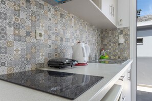 A kitchen with patterned tiles, a kettle, a coffee maker, and a portable iron on the counter.