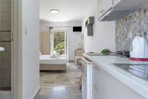 A modern kitchen with a built-in dishwasher, a small dining area, and a bedroom with a view.