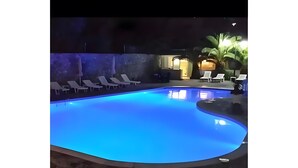 Una piscina con sillas de descanso y una palmera.