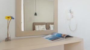 Una habitación con una mesita de noche, un espejo, un teléfono y una revista.