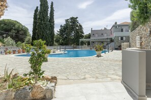 Un espace piscine doté d’un sol en pierre, entouré de plantes en pot et d’arbres.