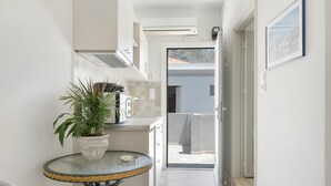 A narrow hallway with a potted plant on a round table, leading to a balcony with a view of the mountains. - Apartment 'No 12' with Shared Pool, Wi-Fi and Air Conditioning (Kalymnos)