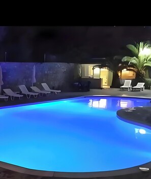 Una piscina con sdraio e una palma.