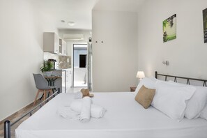 A hotel room with a bed, a desk, a chair, a lamp, and a painting on the wall.