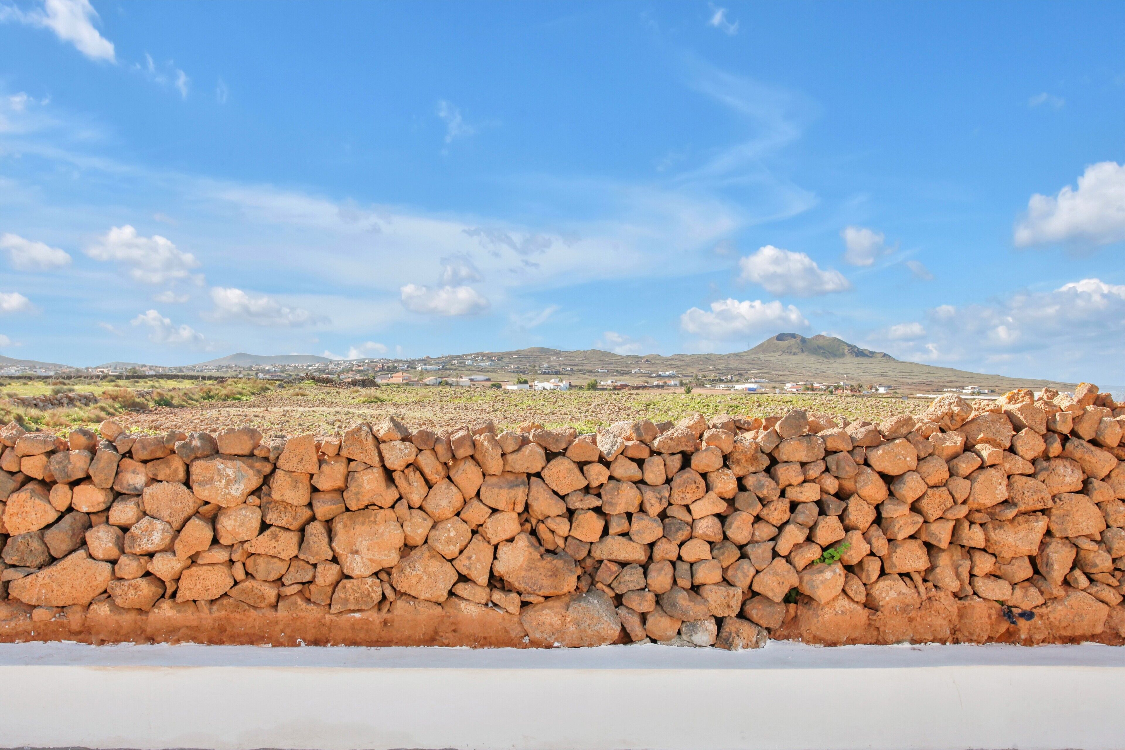Eine Steinsäule mit Blick auf eine weite Landschaft, inklusive Hügel und eines Berges.