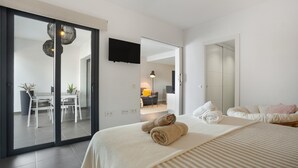 Moderni hotellihuone, jossa on sänky, ruokailutila ja televisio.