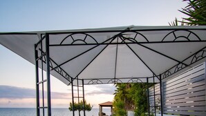 A covered outdoor seating area with wicker furniture and a view of the sea. - Country House 'Navarino Baths' with Sea View, Wi-Fi and Air Conditioning (Vromonérion)