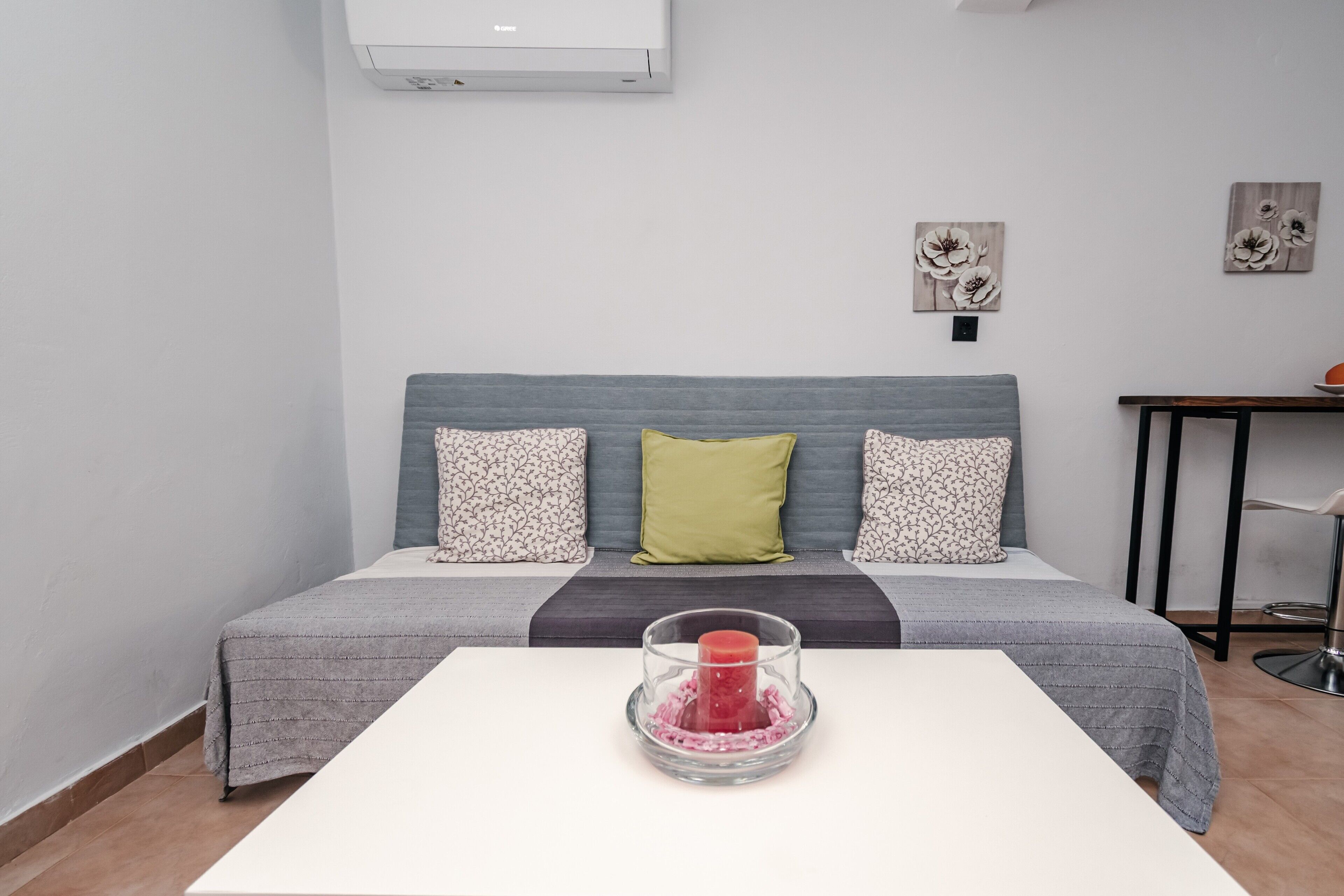 Ein Schlafzimmer mit einem Bett, einem Nachttisch, einer Wandklimaanlage und zwei Wandbildern.
