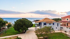 A coastal property with a paved pathway leading to a white building with a tiled roof, surrounded by greenery and overlooking the sea. - Country House 'Navarino Baths' with Sea View, Wi-Fi and Air Conditioning (Vromonérion)