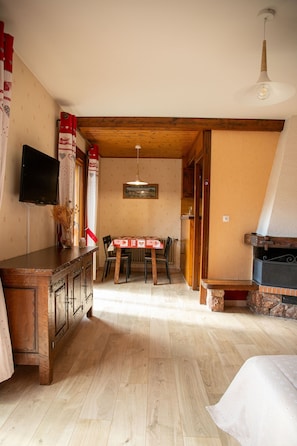 Un interno in legno con un tavolo da pranzo, sedie, una TV a parete e un camino.