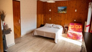 A bedroom with a wooden wall, a bed, a small table, and a chair. - Studio Apartment 'C3 - Chalet Tournier' with Mountain View, Shared Garden and Wi-Fi (Les Gets)