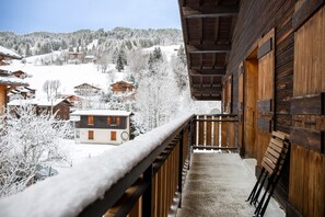 Un balcone in legno con vista su un villaggio innevato e montagne.