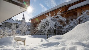 A snow-covered landscape with a wooden building, a church steeple, and a bench in the foreground. - Studio Apartment 'C3 - Chalet Tournier' with Mountain View, Shared Garden and Wi-Fi (Les Gets)