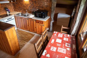 A compact kitchen with wooden cabinets, a microwave, and a sink.