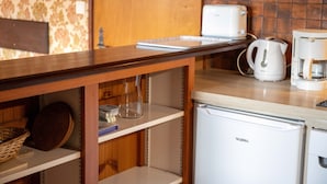 Een keuken met een Valberg koelkast, een broodrooster, een koffiezetapparaat en een houten tafel.