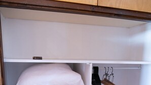 Ein Schrank mit Holzausstattung, weißen Regalen und einer Kleiderstange.