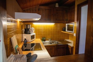A compact kitchen with wooden cabinets, a microwave, a coffee maker, and a sink. - Apartment 'C4 - Chalet Tournier' with Mountain View, Shared Garden and Wi-Fi (Les Gets)
