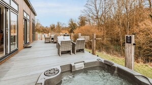 Une terrasse en bois avec des meubles d’extérieur, un jacuzzi et une clôture en bois.