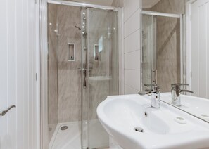 A modern bathroom with a glass-enclosed shower, a white sink with chrome fixtures, and a large mirror. - 2 bedroom accommodation in Bridgnorth (Bridgnorth)