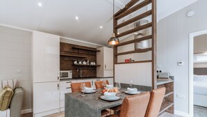 Une cuisine moderne dotée d’un îlot central, d’un coin repas avec des chaises et d’un micro-ondes visible.