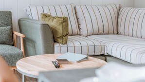 A modern living room with a sectional sofa, a round wooden coffee table, and a grey armchair. - 2 bedroom accommodation in Bridgnorth (Bridgnorth)