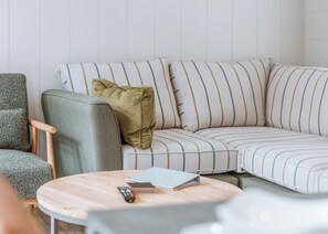 A modern living room with a sectional sofa, a round wooden coffee table, and a grey armchair. - 2 bedroom accommodation in Bridgnorth (Bridgnorth)