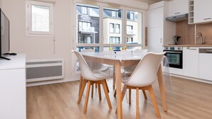 Una cocina moderna con armarios blancos, horno empotrado y ventana con vistas a una zona residencial.