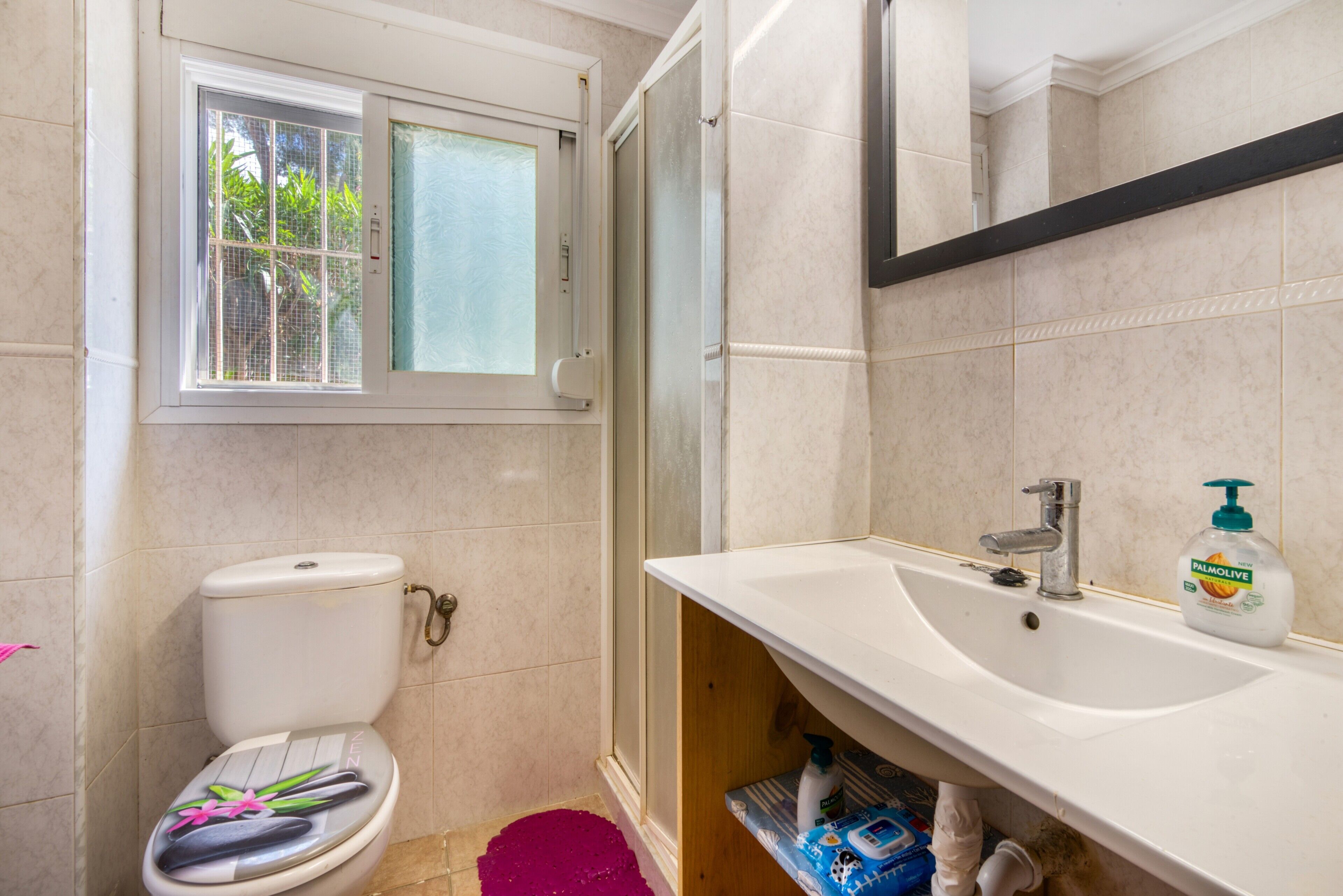 Une salle de bain avec des toilettes, un lavabo, une fenêtre et une douche.