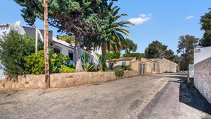 A quiet street with stone walls, a palm tree, and traditional buildings. - Apartment 'La Finca' with Sea View, Wi-Fi and Air Conditioning (Teulada)