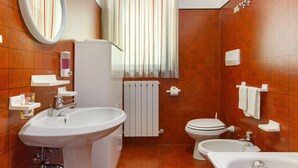 Ein Badezimmer mit Waschbecken, Toilette und Badewanne, einem Spiegel und einem Fenster mit Vorhängen.